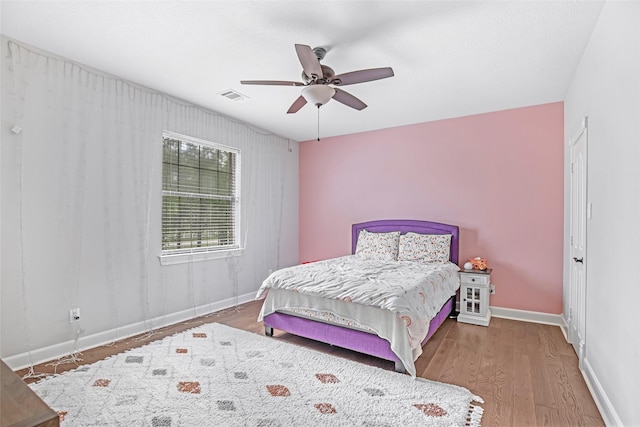 bedroom featuring wood finished floors, baseboards, and ceiling fan