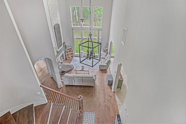 living area with a towering ceiling, wood finished floors, plenty of natural light, a ceiling fan, and arched walkways