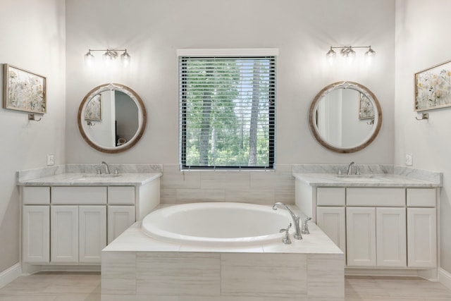 19720 Holly Creek Bnd, Magnolia, TX 77355 - bathroom featuring two vanities, a garden tub, and baseboards
