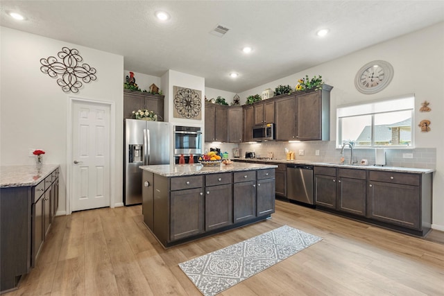 3314 Bastian Rd, Dickinson, TX 77539 - kitchen featuring stainless steel appliances, light wood-style flooring, dark brown cabinetry, a kitchen island, and recessed lighting