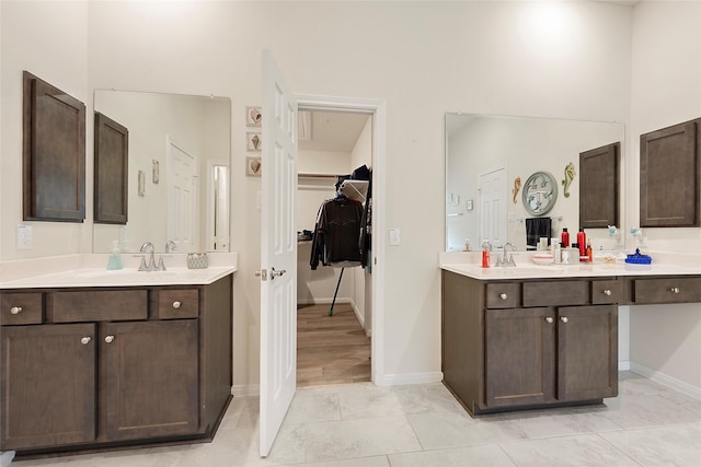 3314 Bastian Rd, Dickinson, TX 77539 - bathroom featuring two vanities, baseboards, a walk in closet, and a high ceiling
