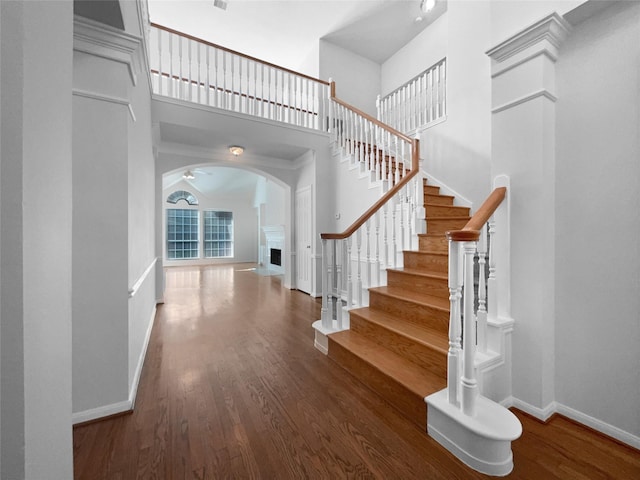 22014 Mission Hills Ln, Katy, TX 77450 - stairway featuring a high ceiling, arched walkways, baseboards, wood finished floors, and a fireplace