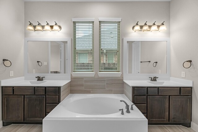1810 Evergreen Bay Ln, Katy, TX 77494 - bathroom featuring two vanities, a garden tub, and wood finished floors