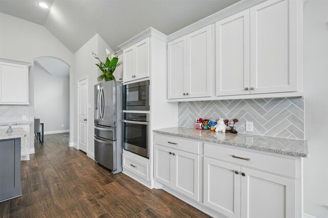 1722 Country Air Ln, Missouri City, TX 77459 - kitchen featuring appliances with stainless steel finishes, white cabinets, arched walkways, lofted ceiling, and tasteful backsplash
