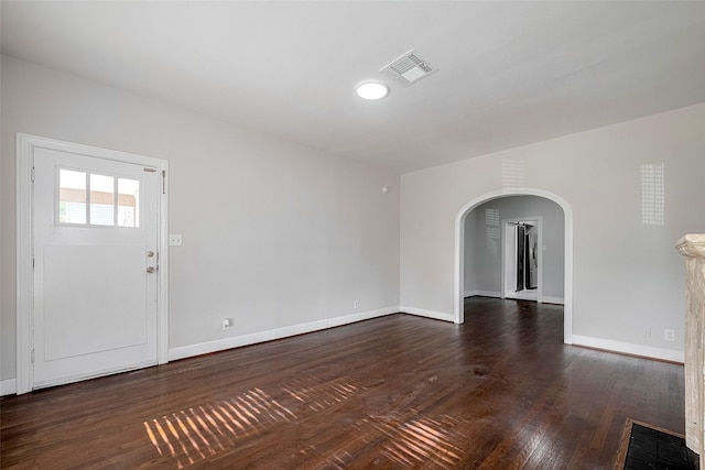 foyer with arched walkways, baseboards, and dark wood-style flooring