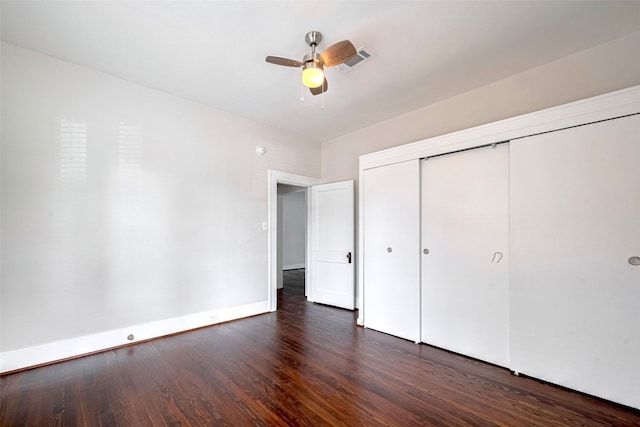 unfurnished bedroom featuring dark wood-style flooring, a closet, baseboards, and a ceiling fan