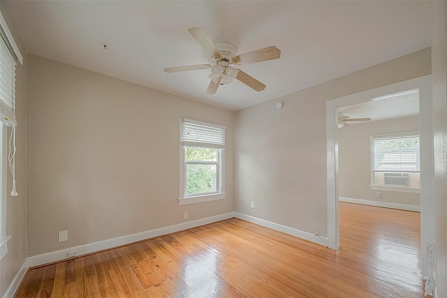 empty room with healthy amount of natural light, a ceiling fan, light wood finished floors, and cooling unit