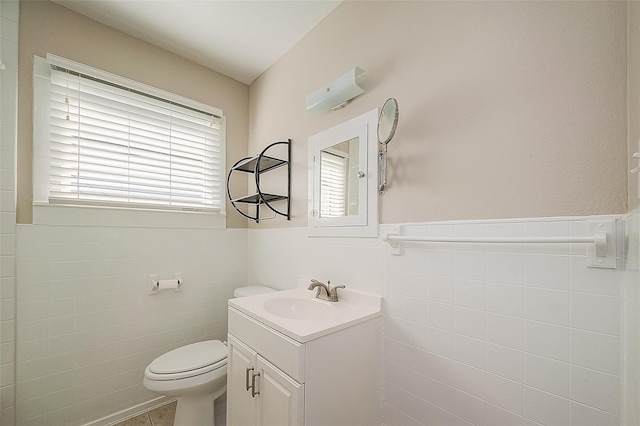 bathroom with toilet, tile walls, vanity, wainscoting, and tile patterned floors