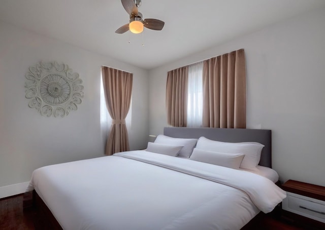bedroom featuring dark wood-type flooring, a ceiling fan, and baseboards