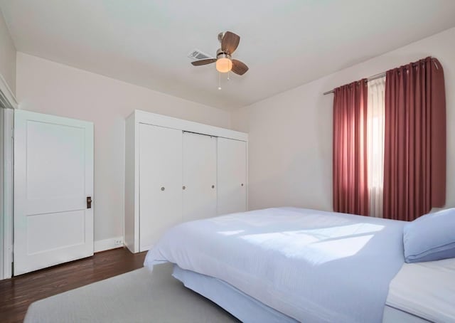 bedroom featuring wood finished floors, a closet, ceiling fan, and baseboards