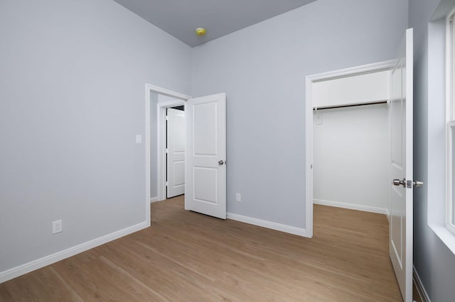 18830 Elegance Ave, Spring, TX 77379 - unfurnished bedroom with light wood-style floors, baseboards, a closet, and a walk in closet