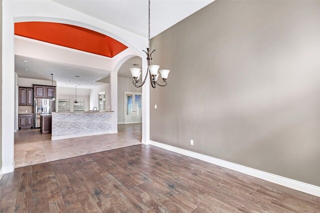 23335 Robinson Pond Dr, New Caney, TX 77357 - unfurnished living room with wood-type flooring, a chandelier, baseboards, and arched walkways