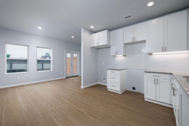 18832 Elegance Ave, Spring, TX 77379 - kitchen with light wood-style flooring, tasteful backsplash, white cabinets, light stone countertops, and recessed lighting