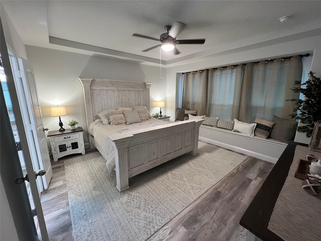 7426 Water Glen Ln, Manvel, TX 77578 - bedroom featuring wood finished floors, a tray ceiling, a ceiling fan, and multiple windows