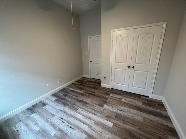 7426 Water Glen Ln, Manvel, TX 77578 - unfurnished bedroom with wood finished floors, baseboards, a closet, and a high ceiling