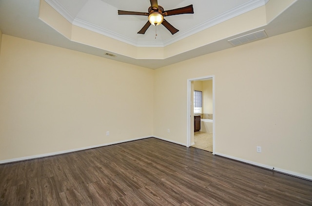 spare room featuring a raised ceiling, wood finished floors, crown molding, a ceiling fan, and baseboards
