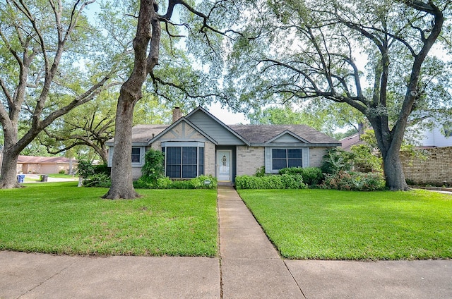 single story home featuring brick siding, a front yard, and a chimney