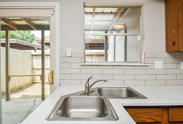 5809 Village Forest Ct, Houston, TX 77092 - kitchen with brown cabinets, backsplash, light stone countertops, a sink, and concrete floors