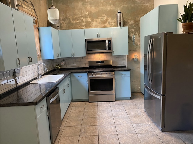 316 S Main St, Seadrift, TX 77983 - kitchen with appliances with stainless steel finishes, a sink, dark countertops, tasteful backsplash, and light tile patterned floors