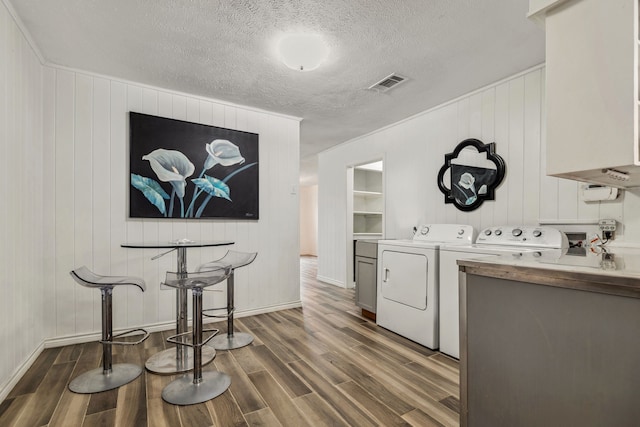 507 Silverdale Dr, Conroe, TX 77301 - laundry area featuring washing machine and dryer, cabinet space, dark wood-type flooring, baseboards, and a textured ceiling