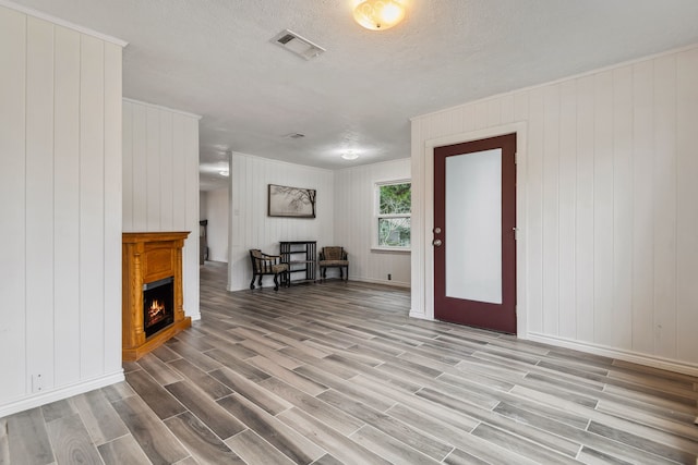 507 Silverdale Dr, Conroe, TX 77301 - living room featuring light wood finished floors, a warm lit fireplace, baseboards, wood walls, and a textured ceiling