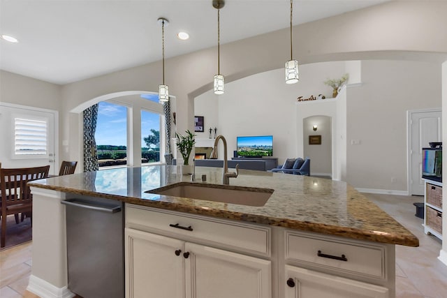 kitchen with arched walkways, a sink, open floor plan, stone countertops, and recessed lighting