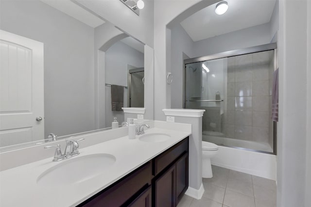 full bath featuring tile patterned flooring, toilet, double vanity, and combined bath / shower with glass door
