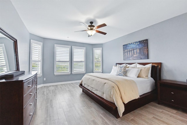 bedroom with light wood-type flooring, ceiling fan, and baseboards