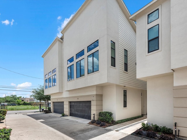 110 N Hutcheson St, Houston, TX 77003 - view of side of home featuring stucco siding, a garage, fence, and driveway