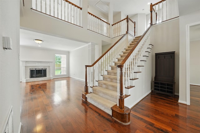 4027 Austin Meadow Dr, Sugar Land, TX 77479 - stairs featuring hardwood / wood-style flooring, a towering ceiling, baseboards, and a high end fireplace