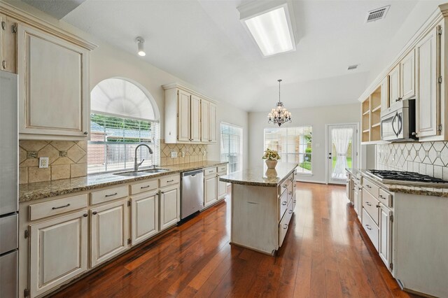 4027 Austin Meadow Dr, Sugar Land, TX 77479 - kitchen featuring stainless steel appliances, cream cabinets, a sink, a center island, and tasteful backsplash