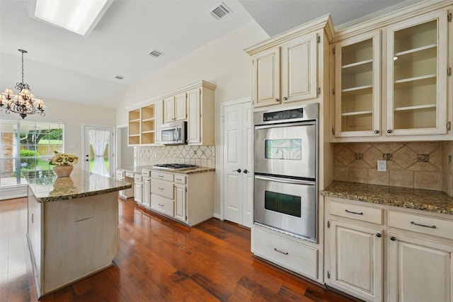 4027 Austin Meadow Dr, Sugar Land, TX 77479 - kitchen with cream cabinetry, appliances with stainless steel finishes, backsplash, a chandelier, and lofted ceiling