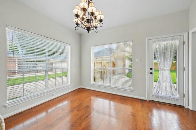 4027 Austin Meadow Dr, Sugar Land, TX 77479 - unfurnished dining area with a chandelier, hardwood / wood-style flooring, and baseboards