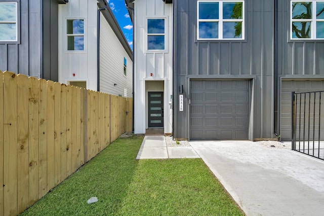 view of front of home with board and batten siding, fence, an attached garage, and driveway