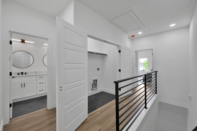 corridor with an upstairs landing, wood finished floors, attic access, and recessed lighting