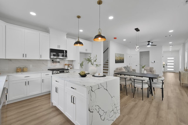 kitchen featuring stainless steel microwave, a ceiling fan, tasteful backsplash, recessed lighting, and open floor plan