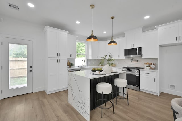 kitchen featuring appliances with stainless steel finishes, white cabinets, light wood finished floors, and recessed lighting