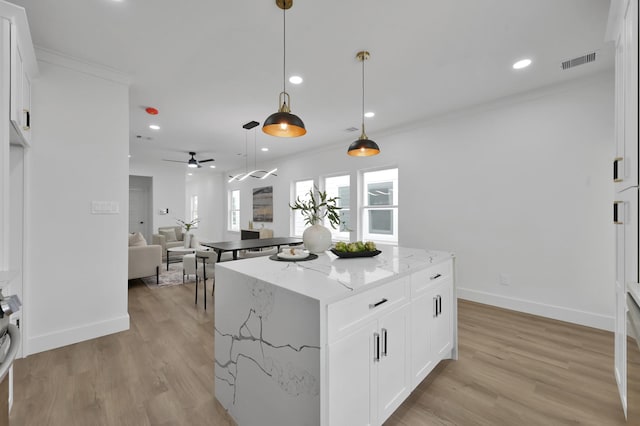 kitchen featuring recessed lighting, white cabinets, light stone counters, light wood finished floors, and hanging light fixtures