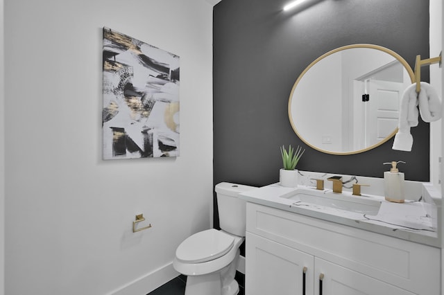 half bath featuring vanity, toilet, and baseboards