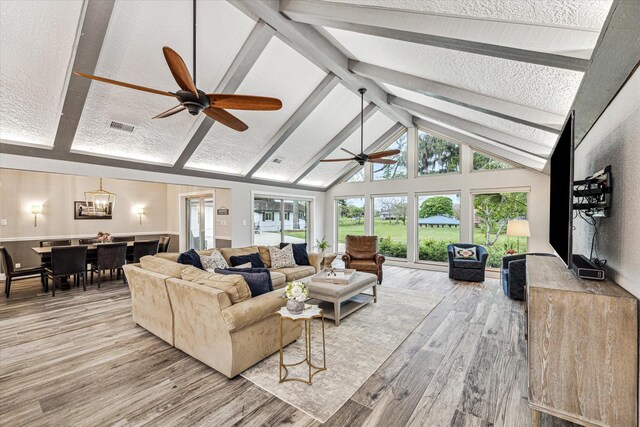 20316 County Road 510b, Brazoria, TX 77422 - living room with wood finished floors, high vaulted ceiling, beamed ceiling, a ceiling fan, and a textured ceiling