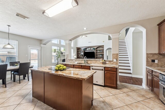 11405 Starlight Bay St, Pearland, TX 77584 - kitchen featuring stainless steel appliances, a sink, light tile patterned floors, backsplash, and a center island