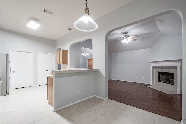 4523 Bridgevillage Dr, Spring, TX 77373 - unfurnished living room with a ceiling fan, arched walkways, a tiled fireplace, vaulted ceiling, and light tile patterned floors