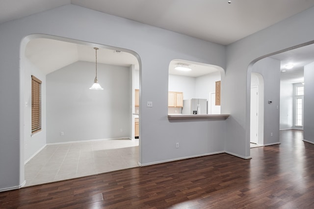 4523 Bridgevillage Dr, Spring, TX 77373 - unfurnished living room featuring lofted ceiling, arched walkways, wood finished floors, and baseboards