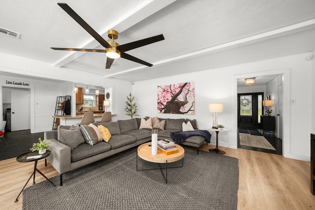 13919 Kimberley Ln, Houston, TX 77079 - living area featuring beam ceiling, light wood-style floors, a ceiling fan, and a textured ceiling
