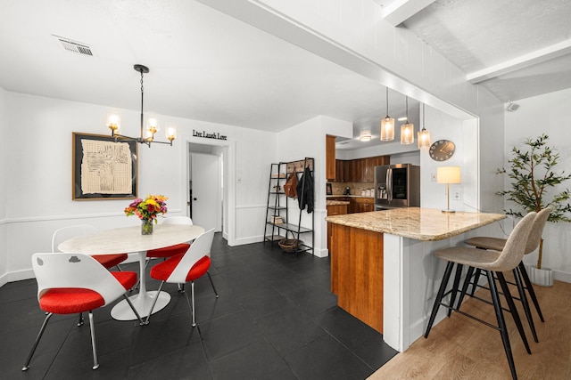 13919 Kimberley Ln, Houston, TX 77079 - kitchen with stainless steel fridge, a peninsula, brown cabinets, a kitchen breakfast bar, and a chandelier