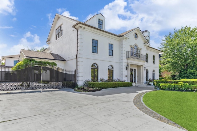 853 Rocky River Rd, Houston, TX 77056 - view of front facade featuring a balcony, curved driveway, fence, stucco siding, and a gate