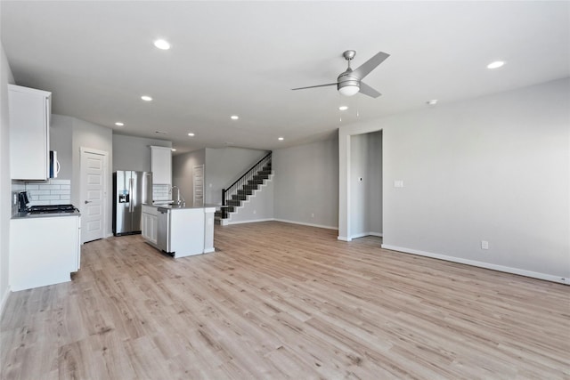 7434 Rivercane Shore Ln, Richmond, TX 77407 - unfurnished living room featuring a sink, a ceiling fan, light wood-style flooring, recessed lighting, and baseboards