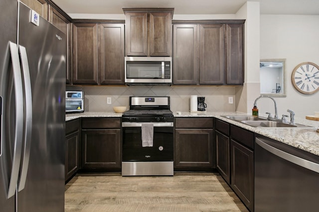 15863 Sundew Prairie Dr, Humble, TX 77346 - kitchen with appliances with stainless steel finishes, a sink, dark brown cabinets, and backsplash