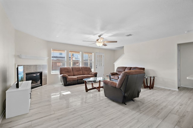 8006 Saffron Ln, Baytown, TX 77521 - living room with a ceiling fan, a tiled fireplace, light wood-style flooring, and baseboards