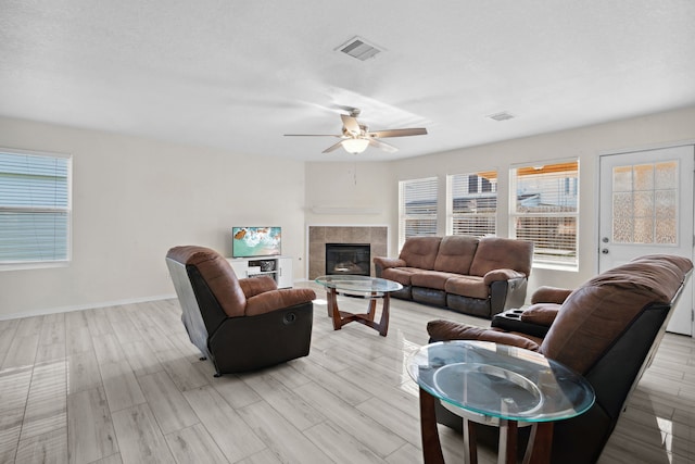 8006 Saffron Ln, Baytown, TX 77521 - living area featuring a ceiling fan, light wood-style floors, a tile fireplace, and baseboards